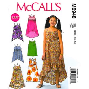 May include: McCall's sewing pattern M6948 for girls' dresses. The pattern includes several dress designs, with a girl modeling a floral print dress. The pattern cover features the McCall's logo and the word "EASY".