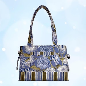 Pode incluir: Uma sacola tote com estampa floral com formato retangular e duas alças. A bolsa apresenta um padrão floral azul e branco com uma seção inferior listrada. As alças e laterais da bolsa também são estampadas.