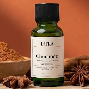 Może przedstawiać: Martwa natura z laskami cynamonu, anyżem gwiazdkowatym i mielonym cynamonem w drewnianej misce. Zielona butelka z napisem "Cinnamon" stoi na drewnianym plastrze. Tło jest w ciepłym, pomarańczowo-brązowym kolorze.