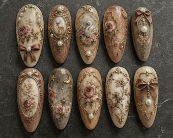 May include: A set of ten almond-shaped press-on nails featuring intricate designs including gold filigree frames, cream and brown floral patterns, a deer, a swan, small white pearls, and sculpted bows in a vintage-inspired aesthetic.