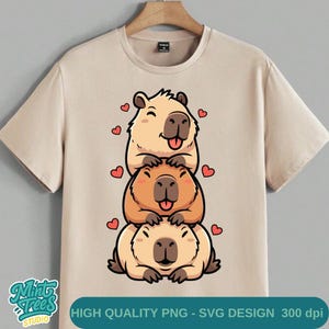 May include: Beige t-shirt featuring a stacked cartoon illustration of three capybaras with hearts. The capybaras are in shades of tan and brown, with their tongues sticking out. The text "HIGH QUALITY PNG - SVG DESIGN 300 dpi" is at the bottom.