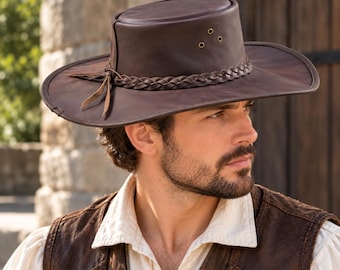 May include: A dark brown leather hat with a wide brim and a flat crown. The hat features a braided leather band around the base of the crown, three small metal ventilation eyelets on the side, and two thin leather ties hanging from the side.