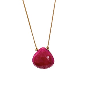 Può includere: Una collana con un ciondolo di pietra preziosa rosa e un cordoncino dorato.
