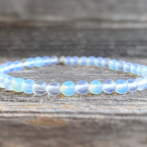 May include: A delicate bracelet made of small, round, light blue opal beads.