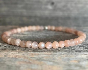 May include: A delicate bracelet made with small, round, peach-colored sunstone beads.
