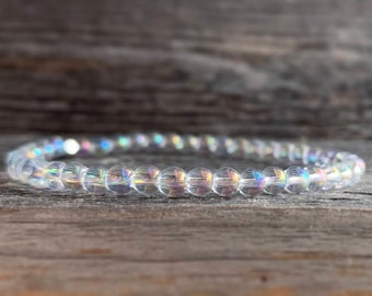 May include: A clear iridescent crystal beaded bracelet. The beads are small and round, and the bracelet is made of a stretchy material.