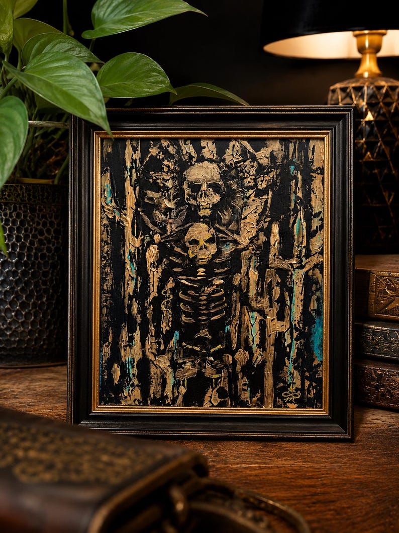 May include: A framed painting featuring a central skeleton figure with a skull head, rendered in thick, textured gold and black paint. The background consists of vertical, abstract strokes of gold, black, and teal, all enclosed in a black frame.