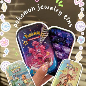 Könnte beinhalten: Eine Sammlung von Pokémon-Schmuckdosen. Die Dosen zeigen verschiedene Pokémon-Charaktere und das Logo des Pokémon-Sammelkartenspiels. Die Dosen haben eine Vielzahl von farbenfrohen Designs, darunter ein Galaxiethema und Bilder von Bisasam, Glumanda und Schiggy.