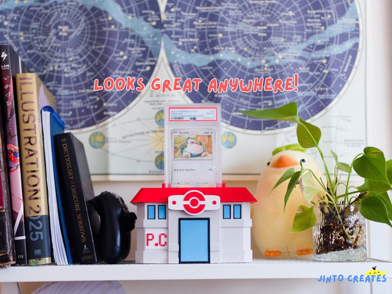 May include: A white and red Pokemon Center display case holding a graded Snorlax trading card. The case is on a shelf with books, a plush toy, and a plant. Text reads "LOOKS GREAT ANYWHERE!"