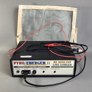 May include: A black Pyro-Energen II electrostatic negatron generator with a white front panel featuring the text BE HEALTHY LIVE LONGER. The device includes a power cord, red and black alligator clip leads, and a square mesh screen attachment.