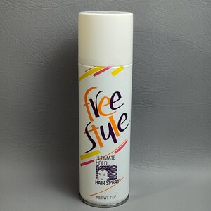 May include: A white hairspray can with a white cap. The can features the word "free style" in orange and purple, with yellow and pink accents. The text "Ultimate Hold" and "Hair Spray" are also visible. Net wt. 7 oz.