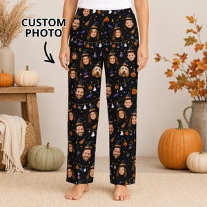 May include: Black pajama pants featuring a repeating pattern of custom photos of faces wearing witch hats, interspersed with orange pumpkins, white ghosts, and purple bats. The fabric has a dark background with a string light design.
