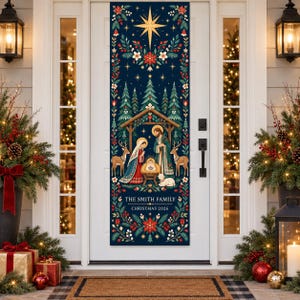 Könnte beinhalten: Ein vertikales, dunkelblaues Türbanner mit einer Krippenszene, einem Stern, Tannenbäumen, Hirschen und floralen Rändern. Der Text lautet THE SMITH FAMILY und CHRISTMAS 2026. Das Design enthält rote und weiße Blumen, grünes Blattwerk und Goldakzente.