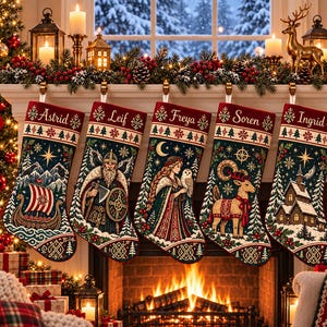 Puede incluir: Cinco calcetines de Navidad colgados en fila, cada uno con una ilustración única de inspiración nórdica y un nombre bordado en la parte superior: Astrid, Leif, Freya, Soren e Ingrid. Los diseños incluyen un barco vikingo, un guerrero, una mujer con un búho, un reno y una cabaña de madera, sobre un fondo azul oscuro con pinos nevados y estrellas.