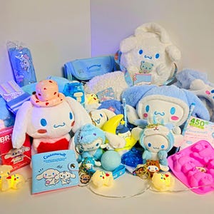 Könnte beinhalten: Eine Sammlung von Cinnamoroll-Artikeln, darunter Plüschtiere, ein Federmäppchen, ein kleines Notizbuch und diverses Zubehör. Die Artikel sind überwiegend weiß und blau, mit einigen rosa und gelben Akzenten. Die Plüschtiere variieren in Größe und Design.