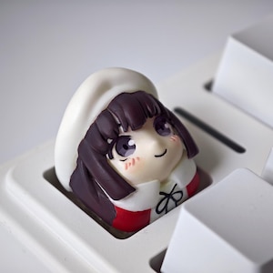 Può includere: Un copritasto personalizzato raffigurante la testa di un personaggio dei cartoni animati, con capelli viola scuro, un cappello bianco e un abito rosso e bianco. Il copritasto è progettato per una tastiera meccanica ed è inserito tra tasti bianchi.