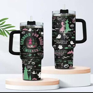 K&ouml;nnte beinhalten: Zwei schwarze Reisebecher mit Griffen, mit einem Design mit den Worten "Changed for Good" und "Wicked". Die Becher haben einen schwarzen Deckel und einen Strohhalm. Das Design umfasst Silhouetten, Geister und Text.