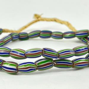 May include: Strands of colorful, striped beads in red, green, blue, and white. The beads are oval-shaped and strung on a natural-colored cord. The beads are a decorative item.