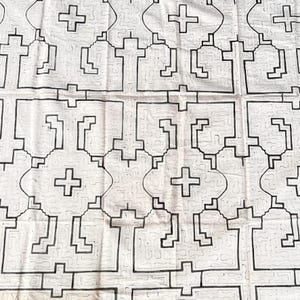 May include: A white fabric textile featuring a repeating geometric pattern in black ink. The design consists of interconnected cross shapes and angular, maze-like lines that form a structured grid across the entire surface of the material.
