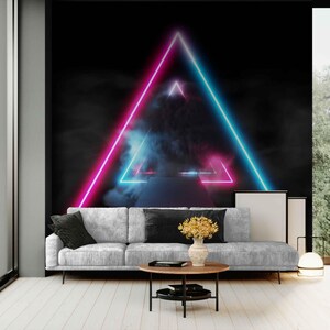 May include: A modern living room with a gray sofa, a round wooden coffee table, and a black and white framed art piece. The focal point is a black wall with a neon pink and blue triangle design, creating a futuristic aesthetic.