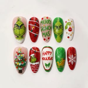 May include: A set of ten artificial nails with Christmas-themed designs. The designs include the Grinch, Christmas trees, ornaments, and the text "Merry Grinch Mas" and "Happy Hooligals". The nails feature glitter and various colors.