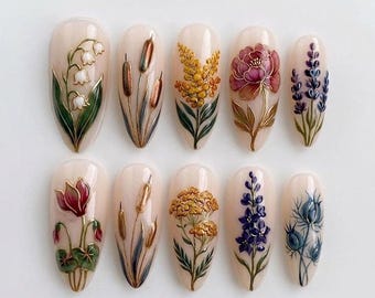 May include: A set of ten almond-shaped press-on nails with a cream-colored base. Each nail features a unique, raised, three-dimensional botanical illustration, including lily of the valley, cattails, yellow wildflowers, a peony, and lavender.