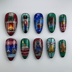 May include: A set of ten Christmas-themed nail art designs. Each nail features a different festive illustration, including a fireplace, nutcracker, Santa in a sleigh, gifts, a gingerbread man, and more. The designs are colorful and detailed.
