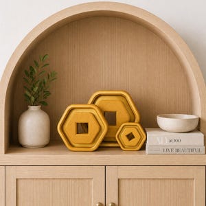 Peut inclure: Un meuble en bois avec une étagère en arc présente des objets décoratifs. Trois plateaux hexagonaux jaunes de différentes tailles sont disposés sur l'étagère. Un petit vase blanc avec de la verdure et un petit bol sont également présents.