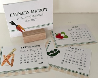 May include: A 2027 mini farmers market calendar set featuring a wooden block stand and individual cards for May, September, and January. Each card displays a month, dates, and illustrations of strawberries, corn, and peas with text.