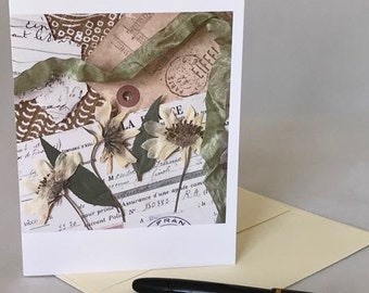 May include: A vintage-style greeting card with a collage of dried flowers, ribbons, and old paper ephemera. The card features a brown and white patterned paper, a green ribbon, and a stamp that says "Eiffel". The text on the card reads "LA FRANCE" and "Assurance d'une année com".