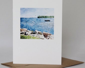 May include: A watercolor painting of a lake scene with a rocky shoreline and a small island in the distance. The water is a light blue color and the sky is a pale blue with a few white clouds.