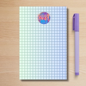 May include: A rectangular notebook with a grid pattern and a gradient color scheme transitioning from light green to blue. A circular graphic featuring the text 2027 in a vibrant, multi-colored pattern is centered near the top. A light purple pen is positioned to the right.