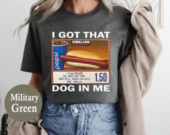 May include: Military green t-shirt with the text "I GOT THAT DOG IN ME." The graphic features a hot dog in a bun, a Pepsi cup, and the text "1/4 POUND PLUS ALL BEEF HOT DOG AND 20 oz. SODA".