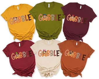 May include: A collection of six short-sleeved t-shirts in various colors, including mustard yellow, olive green, burgundy, and beige. Each shirt features the word "GOBBLE" with a cartoon turkey character in the center.