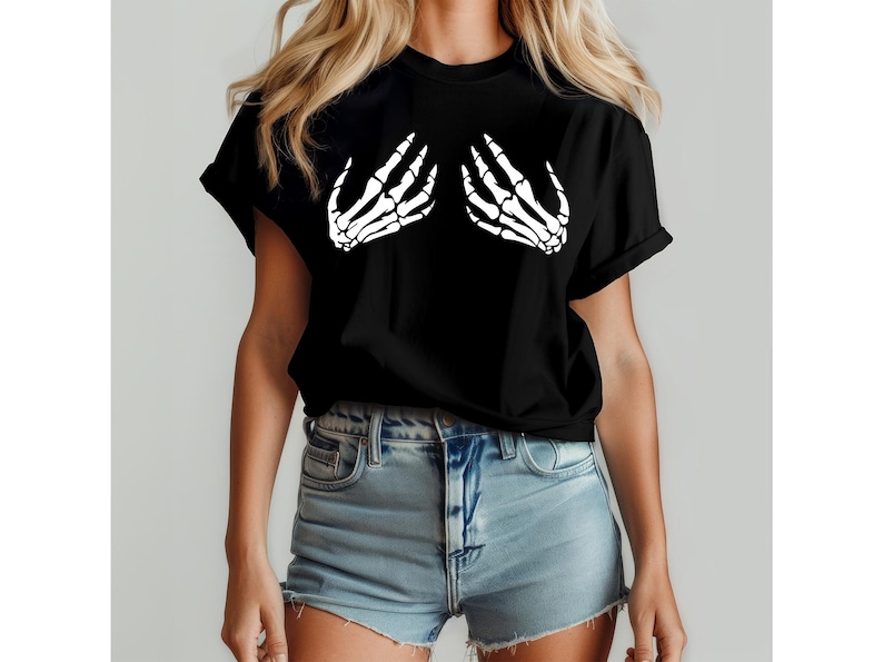 May include: Black t-shirt featuring a white skeleton hand graphic on the front. The graphic depicts two hands in a cupping gesture. The shirt is made of a soft material and has short sleeves.