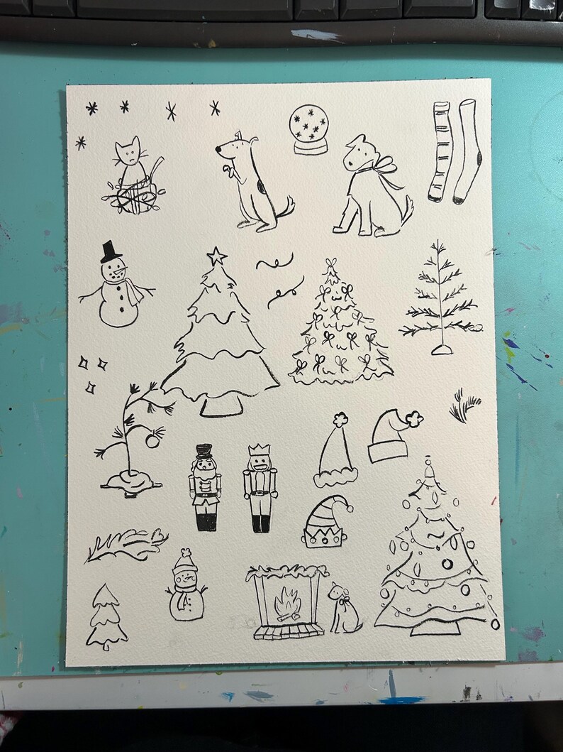 Pode incluir: Ilustra&ccedil;&otilde;es desenhadas &agrave; m&atilde;o em preto e branco de v&aacute;rios objetos com tema natalino, incluindo um boneco de neve, um gato, um c&atilde;o, uma &aacute;rvore de Natal, um quebra-nozes, uma lareira e uma meia.