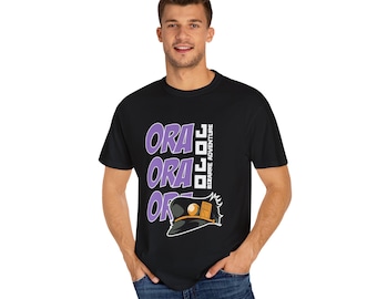 May include: Black t-shirt featuring the text "ORA ORA ORA" in purple, with a stylized hat graphic. The words "JOJO BIZARRE ADVENTURE" are printed vertically on the right side. The shirt is worn by a person.