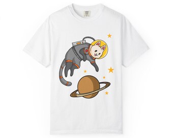 May include: White t-shirt featuring a cartoon cat in a space suit floating near a planet with rings and yellow stars. The cat is wearing a gray and orange spacesuit and a yellow helmet. The design is whimsical and playful.