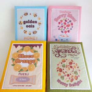 May include: Four boxes of cereal with different flavors and designs. The boxes are yellow, blue, pink, and green. The cereal flavors are "Golden Oats Honey", "Berry Blast", "Choco Orange Muesli", and "Granola Nutty Delight".