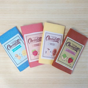 Può includere: Quattro diversi involucri di barrette di cioccolato con design colorati. Ogni involucro presenta un gusto diverso: burro di arachidi, lamponi e mandorle, latte cremoso 30% di cacao e cioccolato bianco pistacchio e fragola.