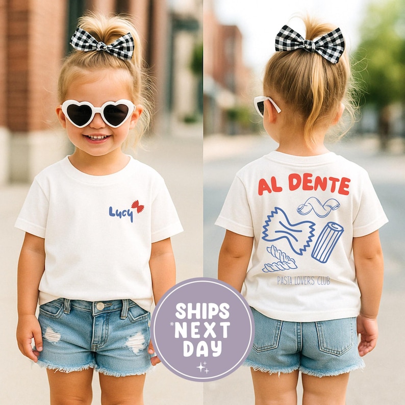 May include: A young child wearing a white t-shirt and denim shorts. The front of the shirt has the name "Lucy" with a red and blue bow. The back of the shirt says "AL DENTE" with pasta illustrations and "PASTA LOVERS CLUB". The child is wearing heart-shaped sunglasses and a black and white bow.