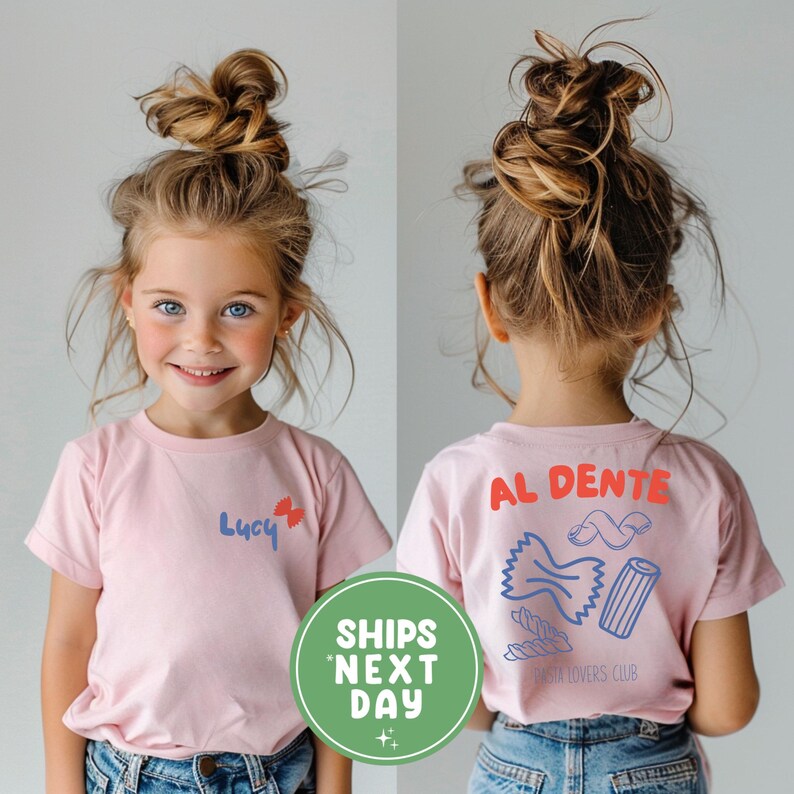 May include: A pink t-shirt with the name "Lucy" and a butterfly graphic on the front. The back of the shirt features the words "AL DENTE" and pasta illustrations. The shirt is part of the "PASTA LOVERS CLUB" collection.