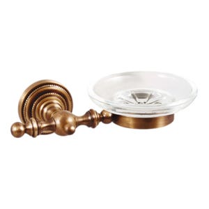 May include: A wall-mounted soap dish with a vintage aesthetic. The dish features a clear glass bowl set on a bronze-colored metal base. The mounting hardware is also bronze, with decorative detailing. The overall design is ornate and classic.