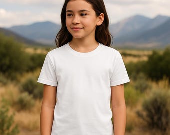 May include: A white, short-sleeved t-shirt. The shirt has a crew neck and a simple, classic design. The model is wearing blue jeans. The background features a natural landscape with mountains and greenery.