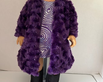 May include: A purple faux fur coat with a silver sequined dress underneath. The doll is wearing black boots.