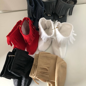 Könnte beinhalten: Ein Set mit acht Miniatur-Stiefeln mit Fransen. Die Stiefel sind in vier verschiedenen Farben: Marineblau, Rot, Weiß und Schwarz. Die Stiefel sind aus verschiedenen Materialien gefertigt, darunter Leder, Wildleder und Stoff.