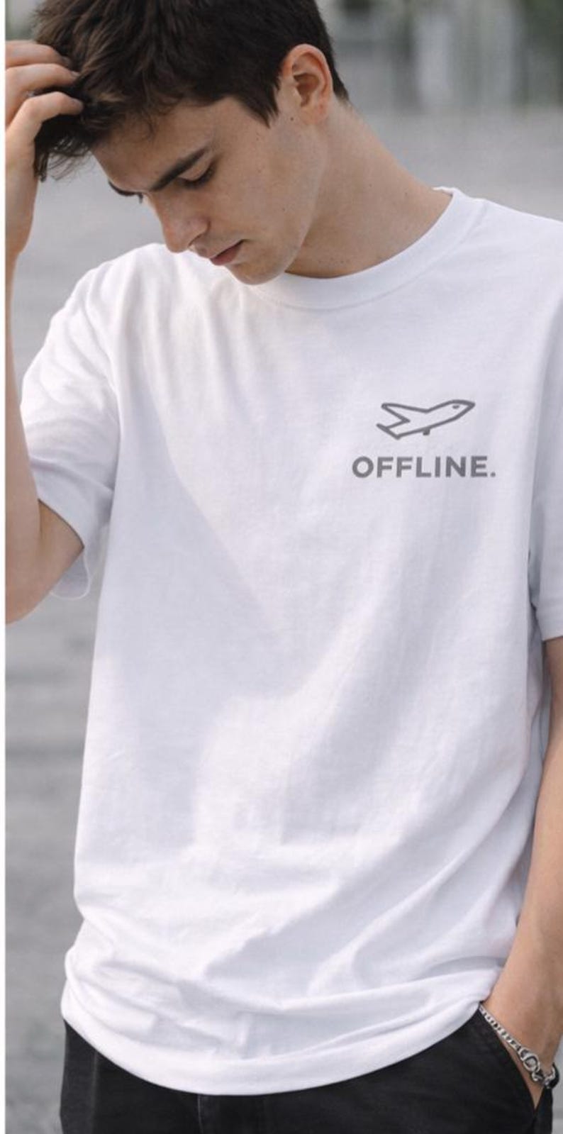 Puede incluir: Camiseta blanca con un gr&aacute;fico de avi&oacute;n gris y la palabra "OFFLINE." impresa debajo. La camiseta est&aacute; hecha de un material suave y tiene mangas cortas.