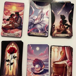 Könnte beinhalten: Sechs rechteckige Tarotkarten in zwei Reihen angeordnet. Die Karten zeigen Illustrationen von The Lovers, Justice, Ace of Swords, Ace of Wands, Ace of Cups und Ace of Pentacles, jeweils mit Motiven wie einem gläsernen Schuh, einer Rose und einer Perle.