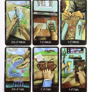 May include: A collection of six tarot cards with vibrant illustrations. The cards show hands interacting with objects like a paintbrush, a keyboard, and cups. Each card is labelled at the bottom with titles such as "Ace of Wands" and "4 of Cups".