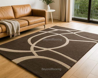 May include: A rectangular area rug featuring a dark brown base with a large, light beige geometric pattern of intersecting circles and curved lines. The text Beyondflooring is visible in two locations on the surface of the rug.